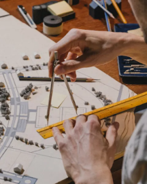 Paisajista utilizando un compás y una regla sobre el plano de un proyecto de espacio exterior