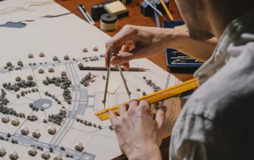 Paisajista utilizando un compás y una regla sobre el plano de un proyecto de espacio exterior