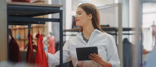 Profesional revisando la colocación de prendas con una tableta en una tienda.