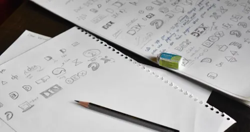 lápiz encima de folio con bocetos de logos