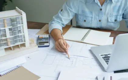 Persona trabajando con un ordenador, hojas en blanco y calculadora